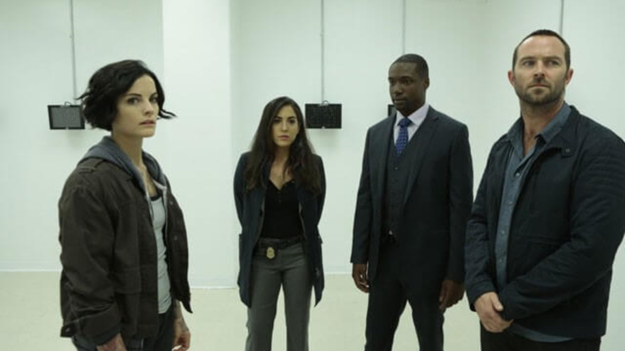 Two female and two male characters standing in a white room in Blindspot
