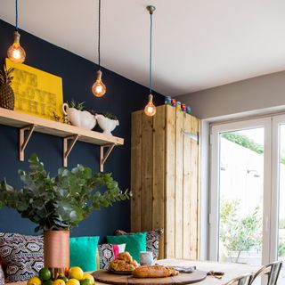 A dining room with pendant lights switched on and hanging over the dining table