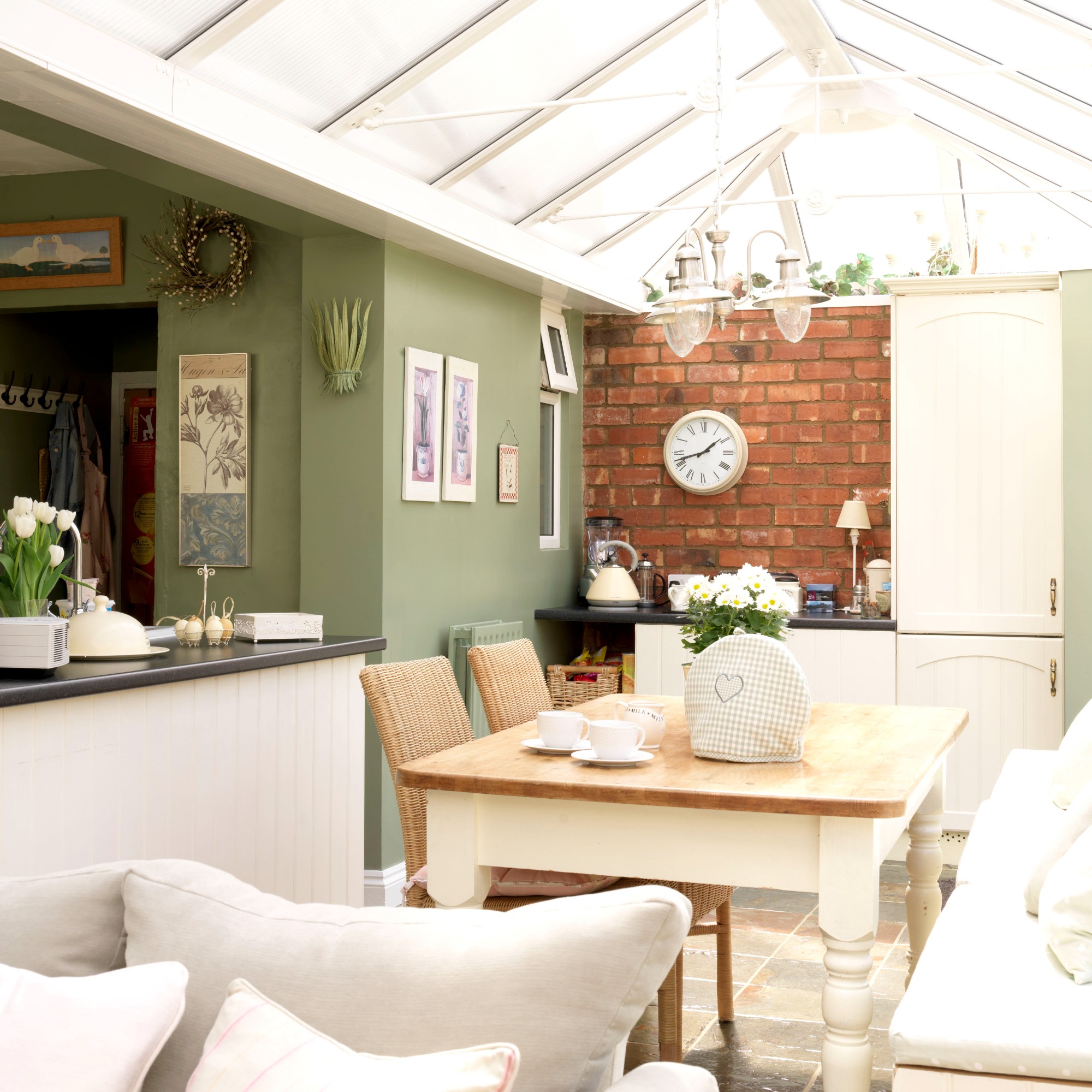 A sage green-painted conservatory seemlessly connected to the rest of the home