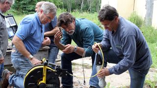 Craig Tester, Rick Lagina and Marty Lagina crouching over equipment in The Curse of Oak Island season 12