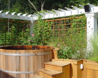 A custom-built hot tub with steps and trellis in a residential backyard