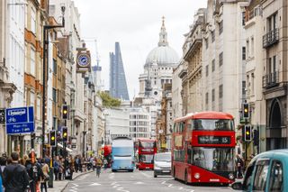 Busy street in City of London with heavy traffic, crowds of people and dome St. Paul's Cathedral