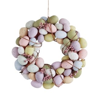 A circular egg wreath with pastel colored eggs adorning it in green, light blue, pink, and purple shades, and pink berry twine decorations wrapped around it