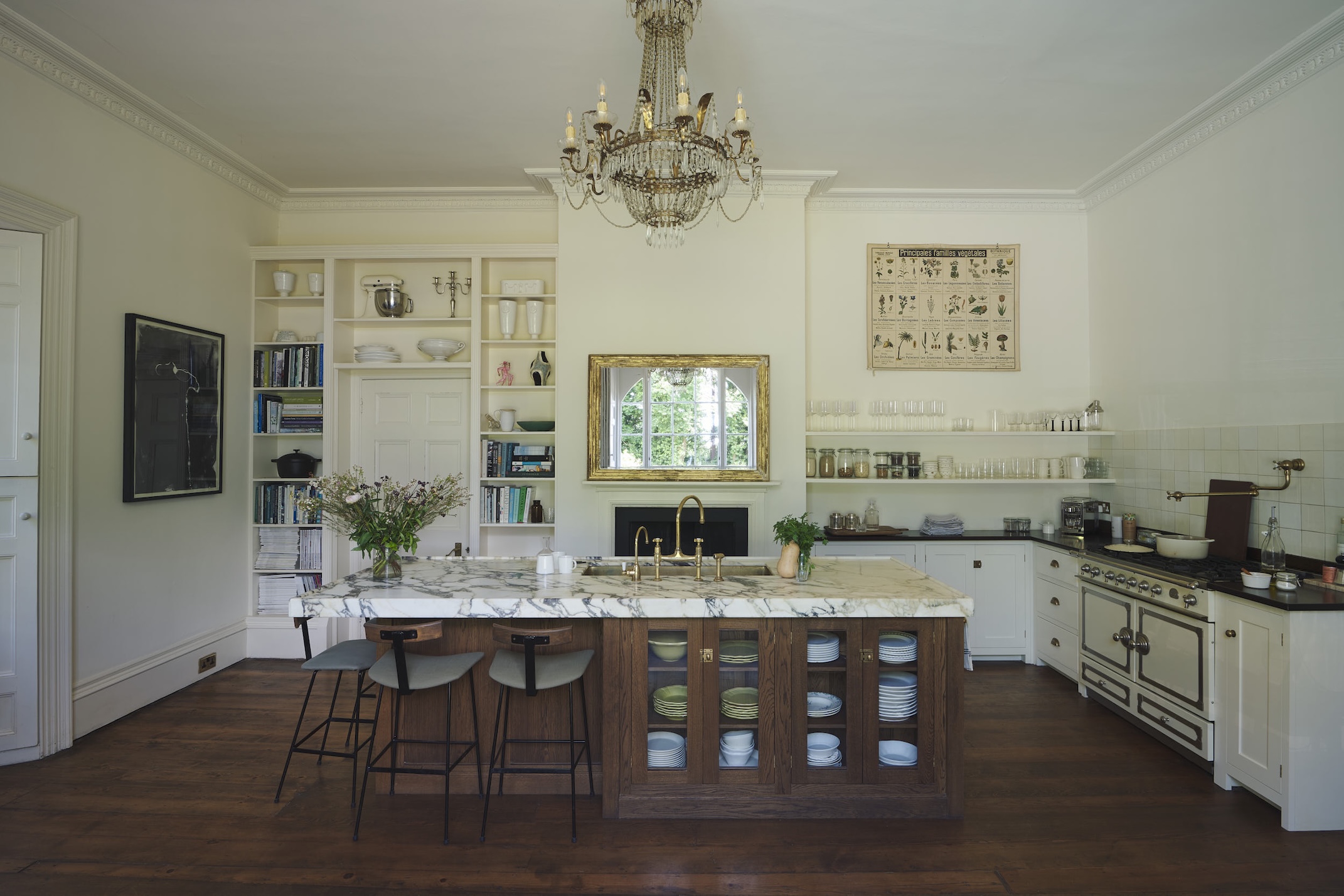 A classical English country kitchen with original architectural features, a dark wood island and richly veined countertop.