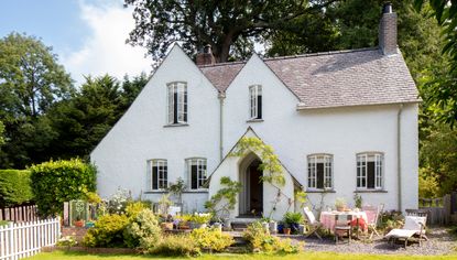 exterior of a whitewashed arts and crafts country home in summer with outdoor table and chairs