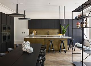 a black and brass modern kitchen with shelving in the foreground