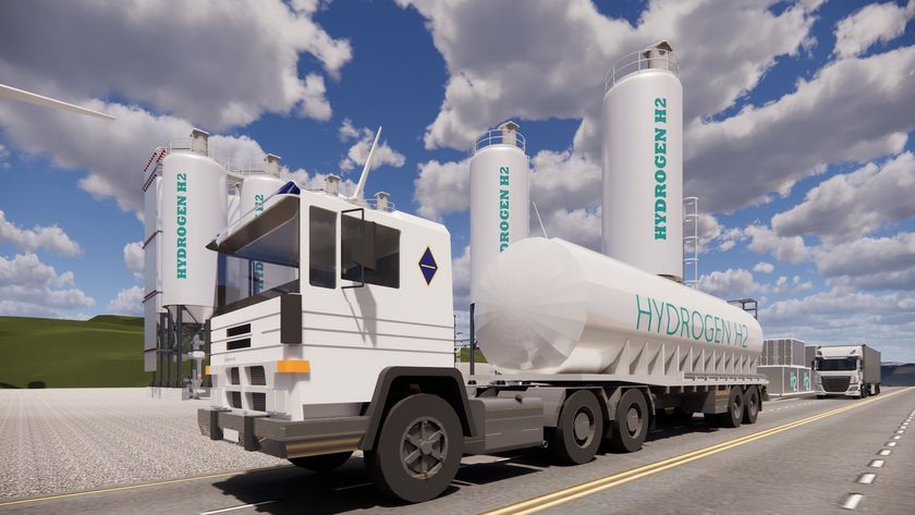 white hydrogen tank truck in front of two hydrogen storage tanks.