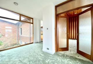 Floor to ceiling windows as well as mint carpet leading to wooden frame double doors