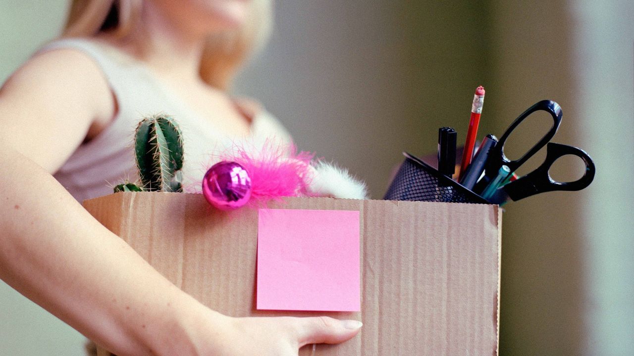 Woman carrying stationery and desk content in a box