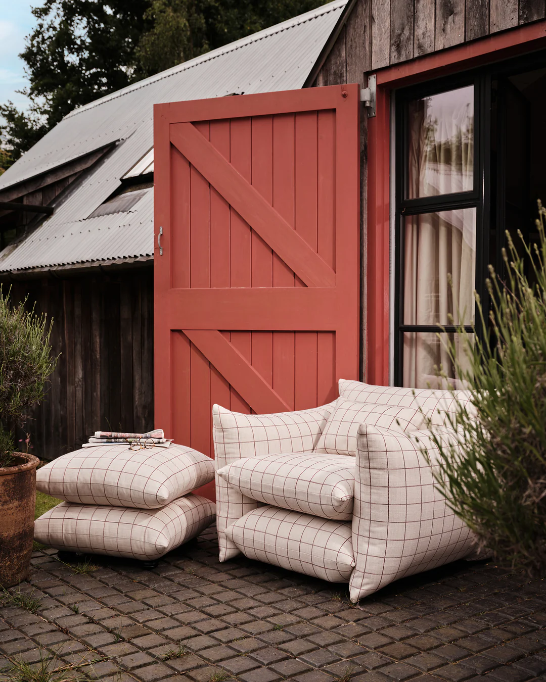 Buchanan Studio outdoor studio armchair in grid check against a clay-red door