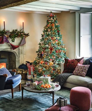Cozy living room with decorated christmas tree, fireplace, cushions on floor, sofa