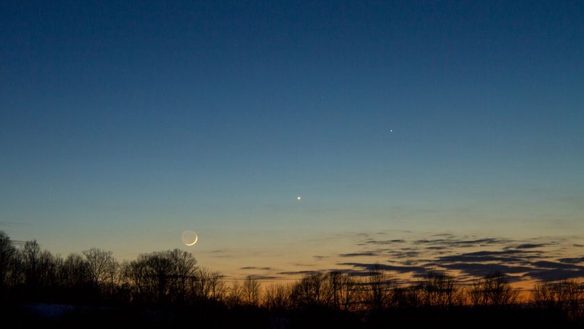 A orange and blue night sky with a glowing crescent moon and a bright dot for the planet Mercury with a series of silhouettes of trees in the foreground