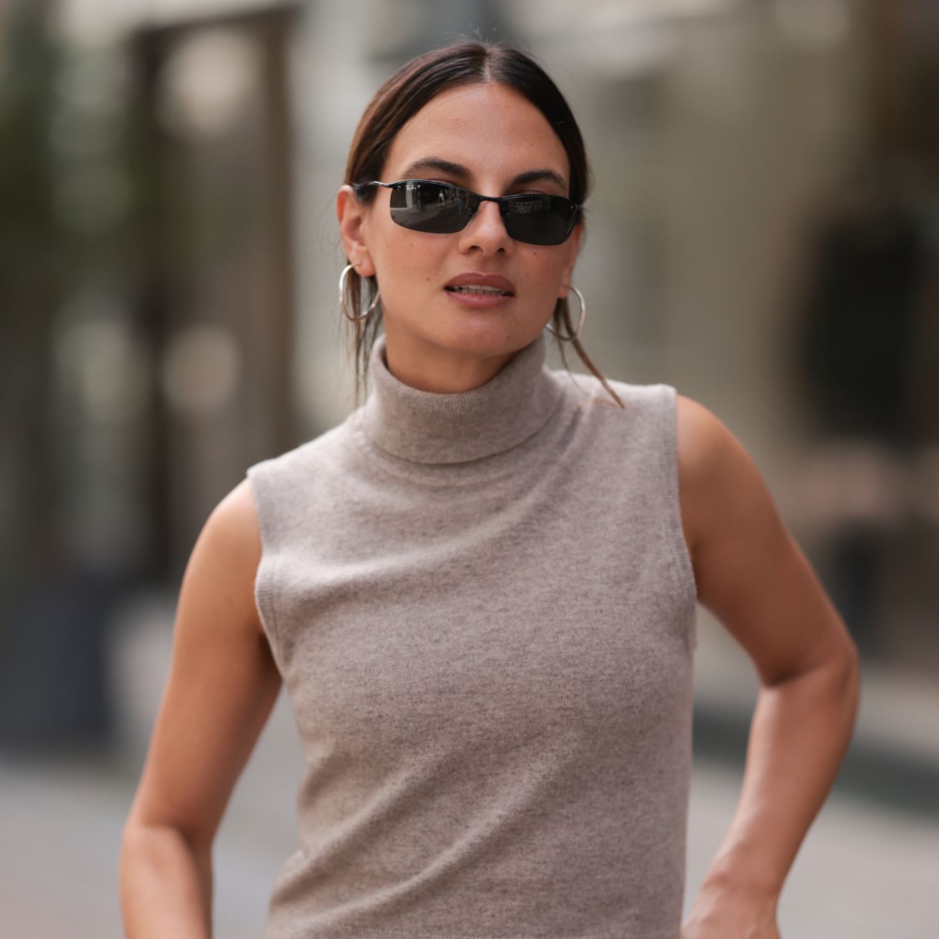 Anna Winter is seen wearing sunglasses with a fine black frame from Ray Ban, silver hoop earrings, a beige knitted tank top with turtleneck, two-tone leather pants in beige and brown with decorative seams, silver bangles, the “Love“ ring and the “Juste un Clou“ ring in yellow gold from Cartier, and a black leather bag featuring small pockets of various sizes from Miu Miu before the Filippa K SS25 Lunch Event during day two of the Copenhagen Fashion Week