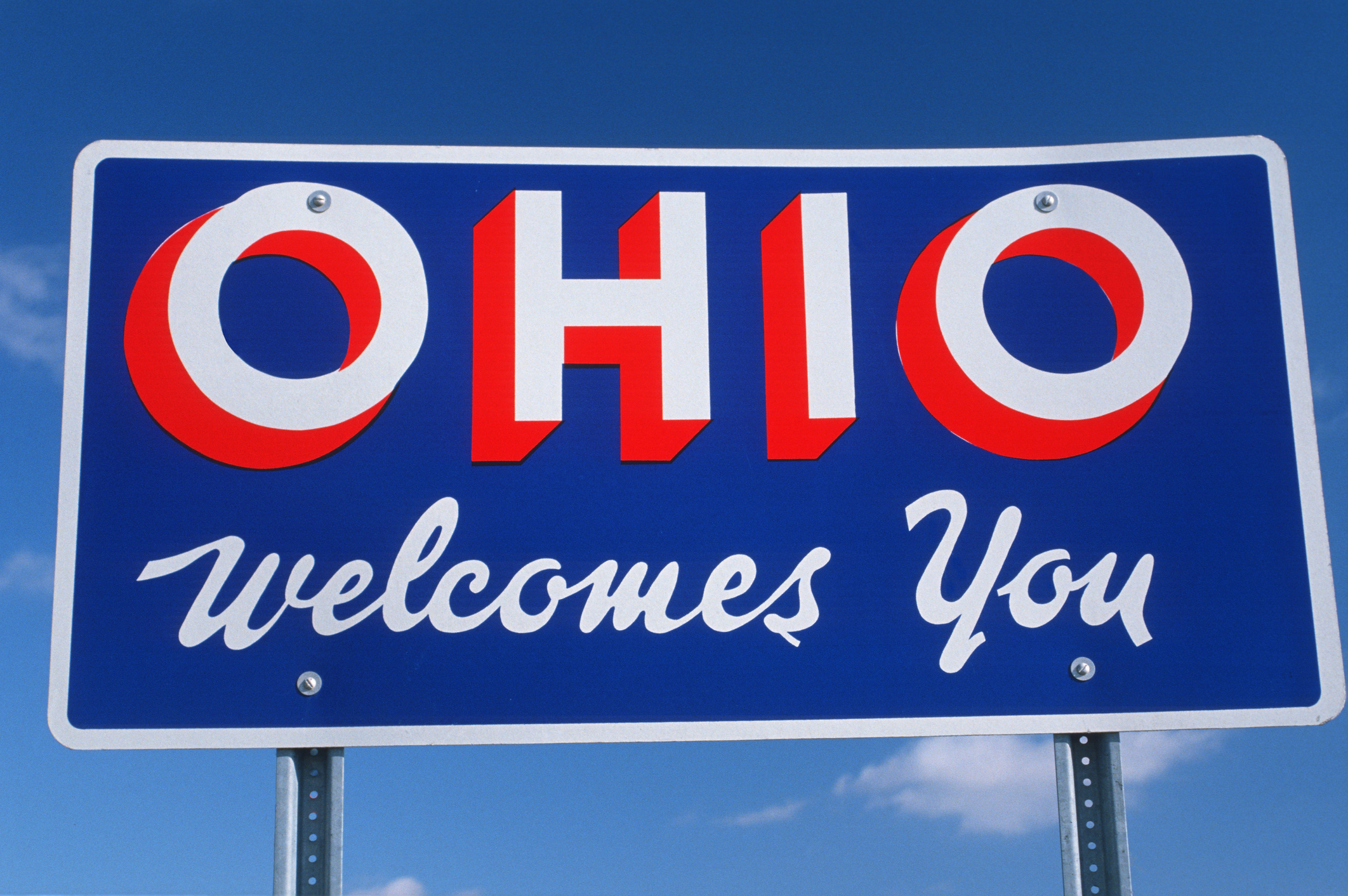 A sign that reads "Welcome to Ohio" against a blue sky 