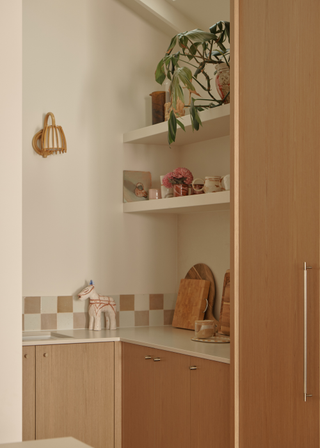 small kitchen nook with light oak cabinetry and a checkerboard tile trim