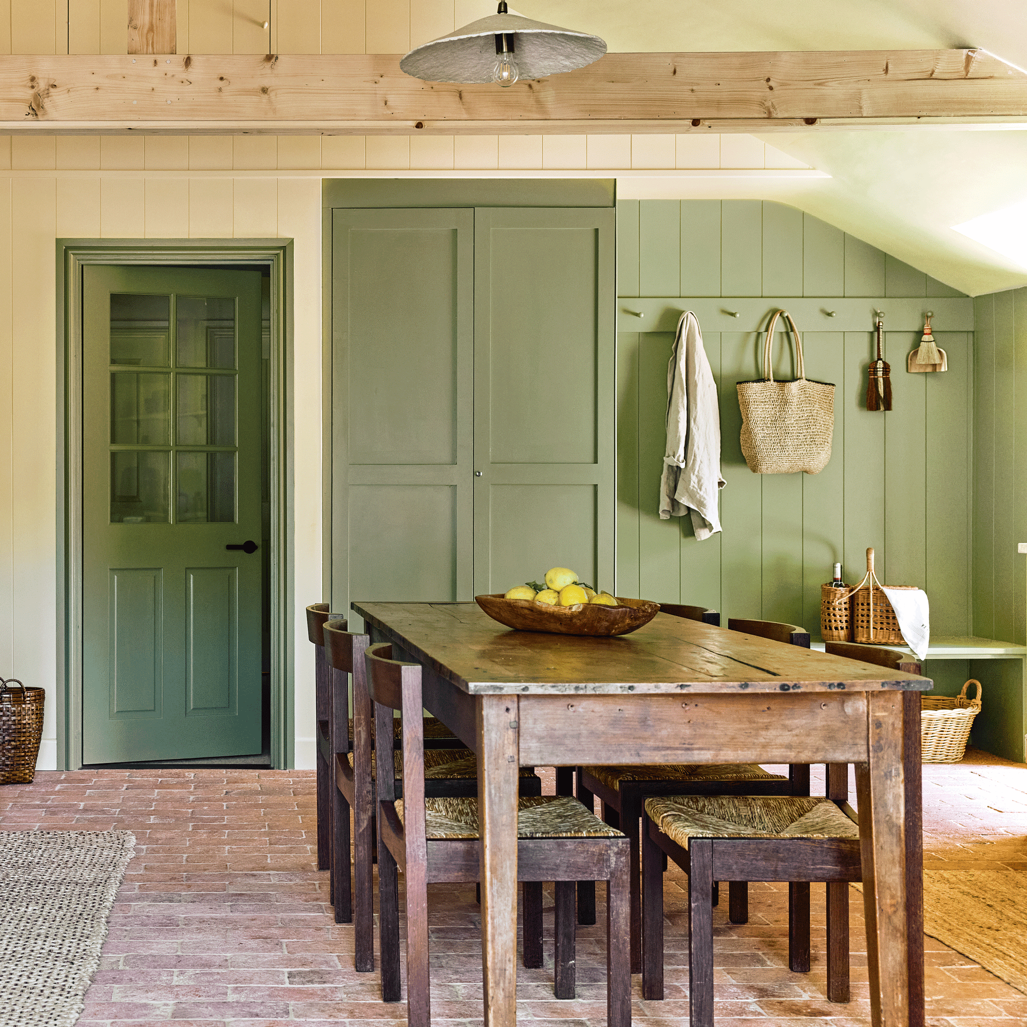 an open plan kitchen diner with a green boot room area and an old reclaimed table and chairs