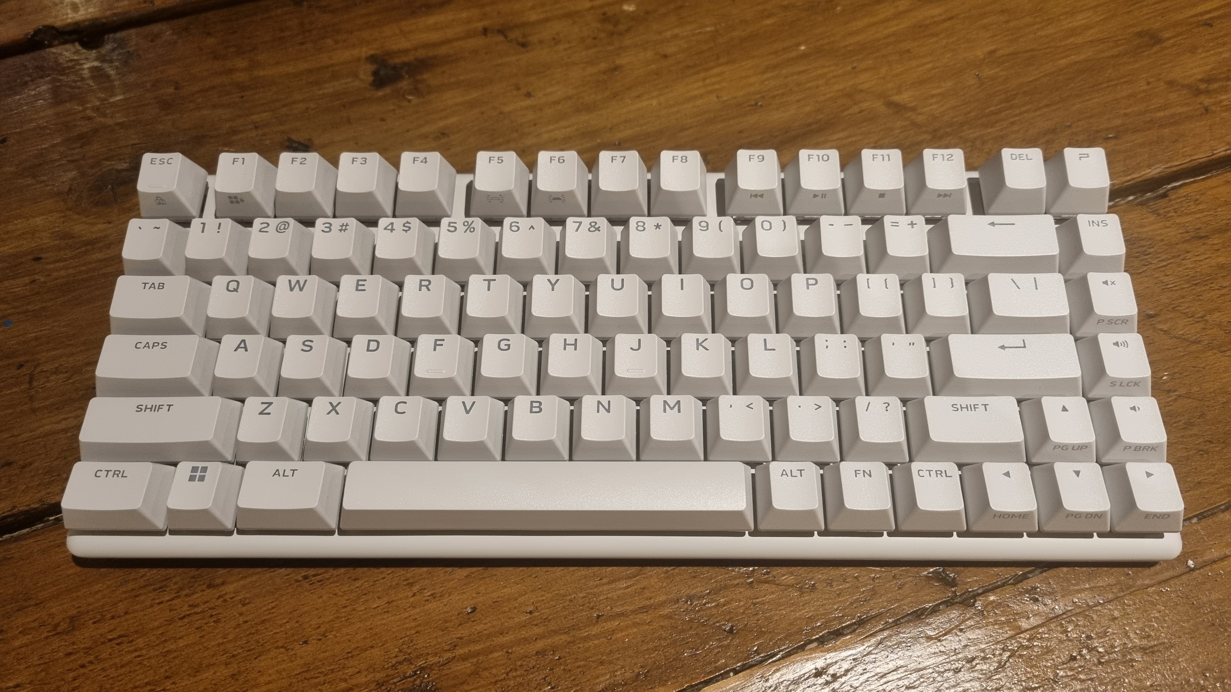 The Alienware Pro Wireless Gaming Keyboard with the RGB lighting turned off, on a wooden desk