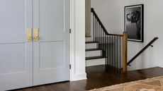 blue entryway closet with gold handles next to a staircase going up and down 