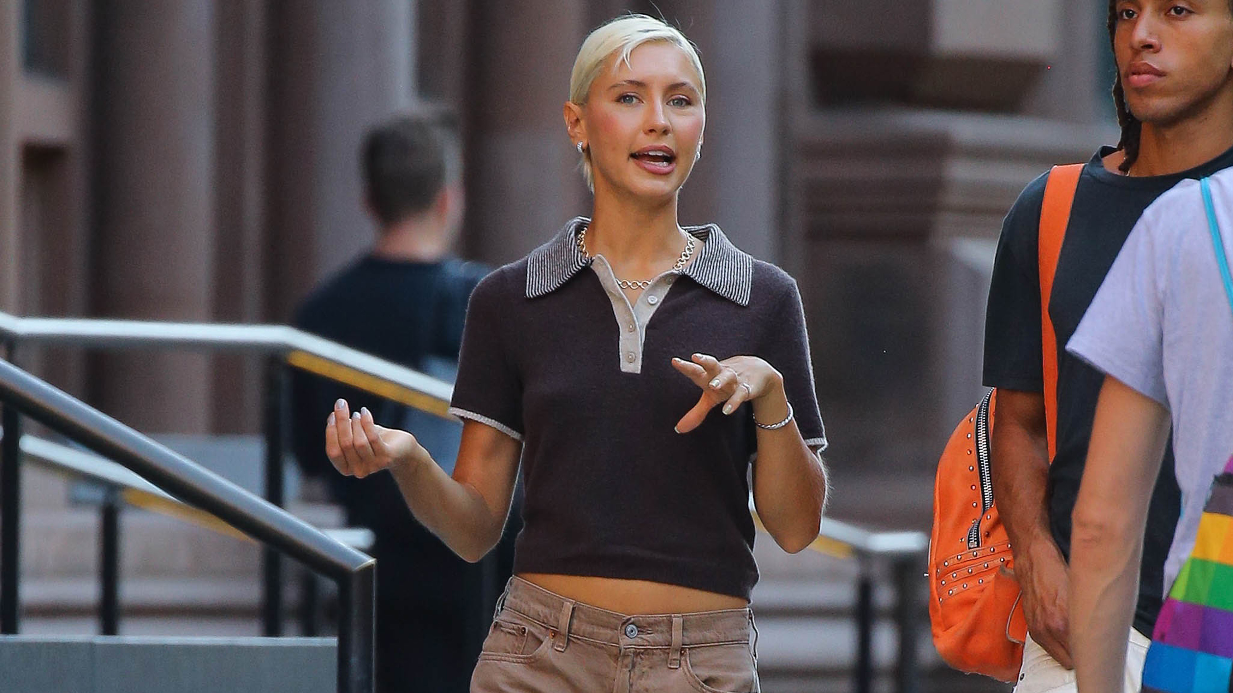 Iris law wears a brown polo shirt and low-rise khaki jeans.