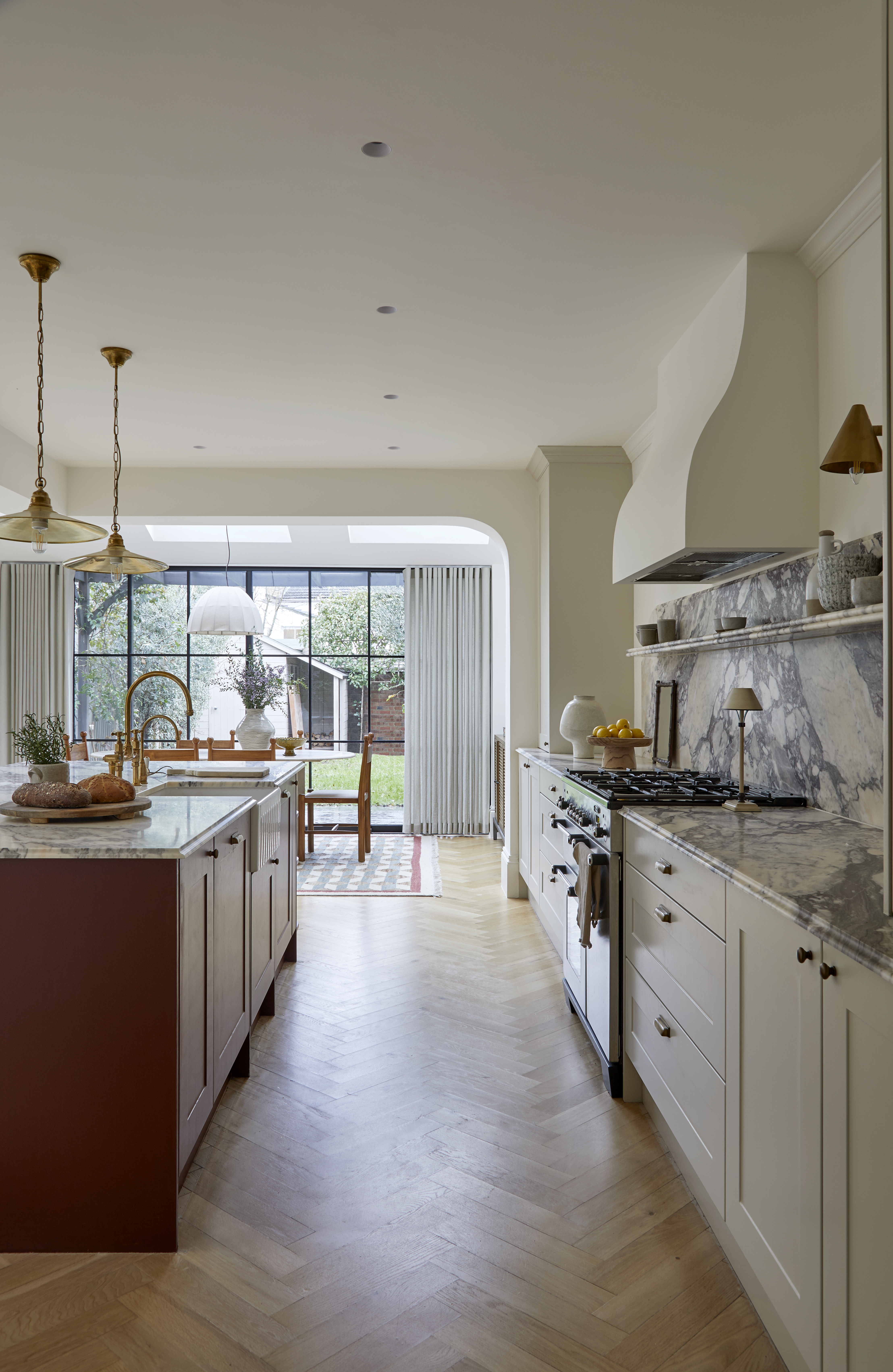 beautiful kitchen extension with a burgundy island, off-white cabinetry, and marble counters