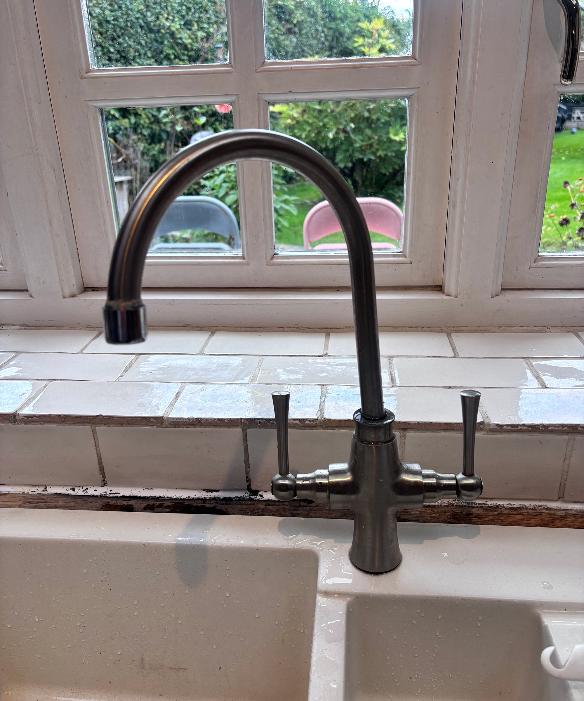 old brushed nickel kitchen tap with tiled window sill
