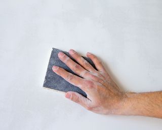 hand sanding a white wall