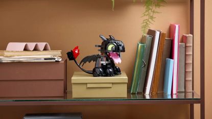 Lego Toothless model sat on a box, on a bookshelf