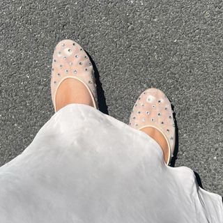 Close-up photo of woman wearing white silk skirt and bedazzled mesh shoe trend.