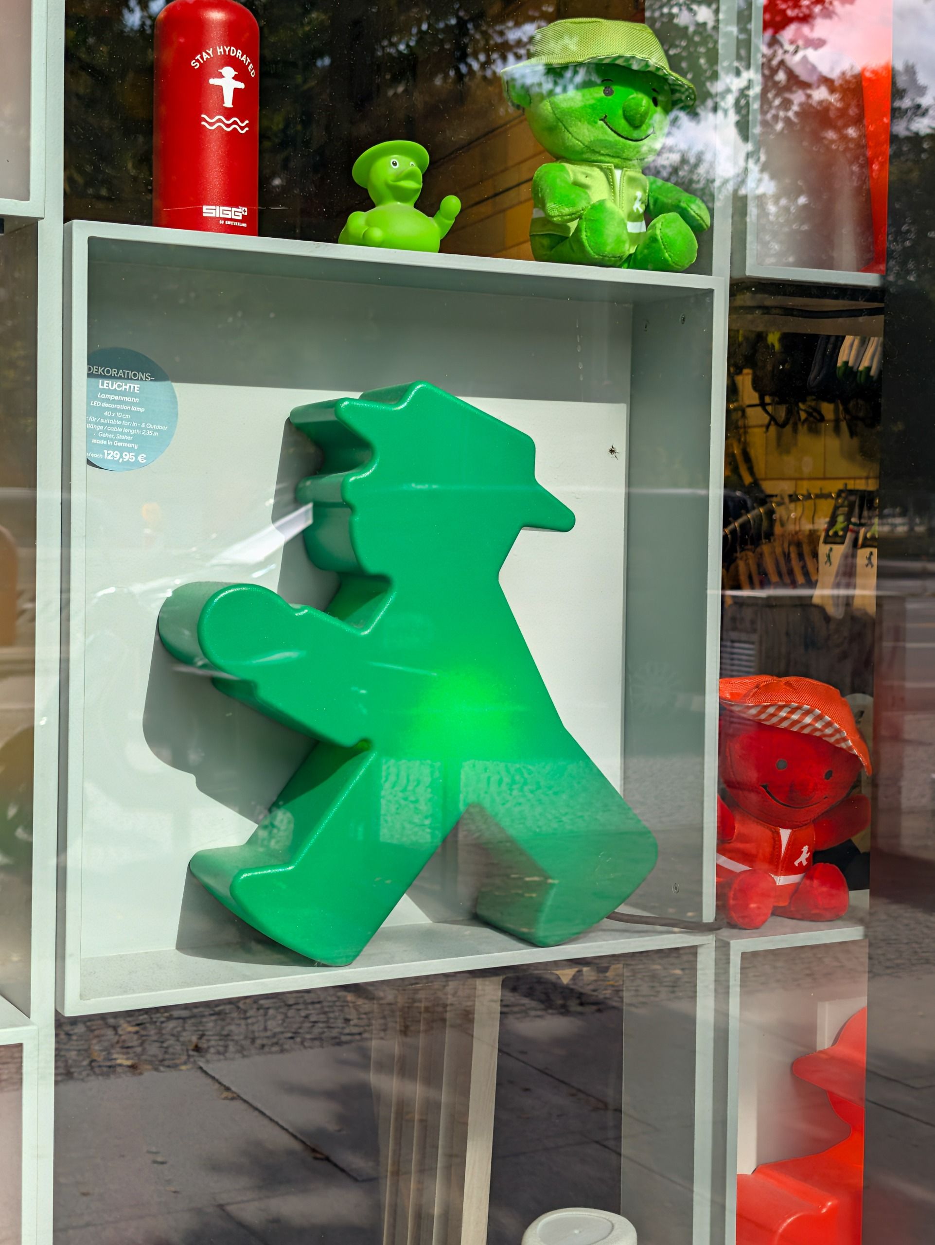 Green Ampelm&auml;nnchen pedestrian figure and merchandise displayed in a Berlin shop window.