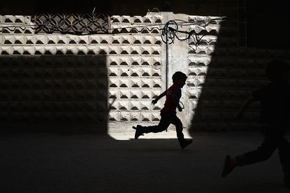 A Syrian child runs down the street.