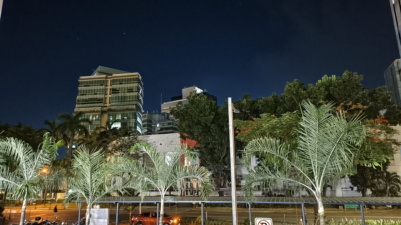 A nighttime cityscape seen from a building, showcasing the illuminated city lights and its architectural beauty