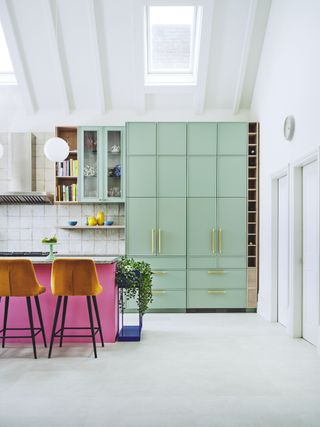 apartment kitchen with pink kitchen island, green cabinetry, white paint