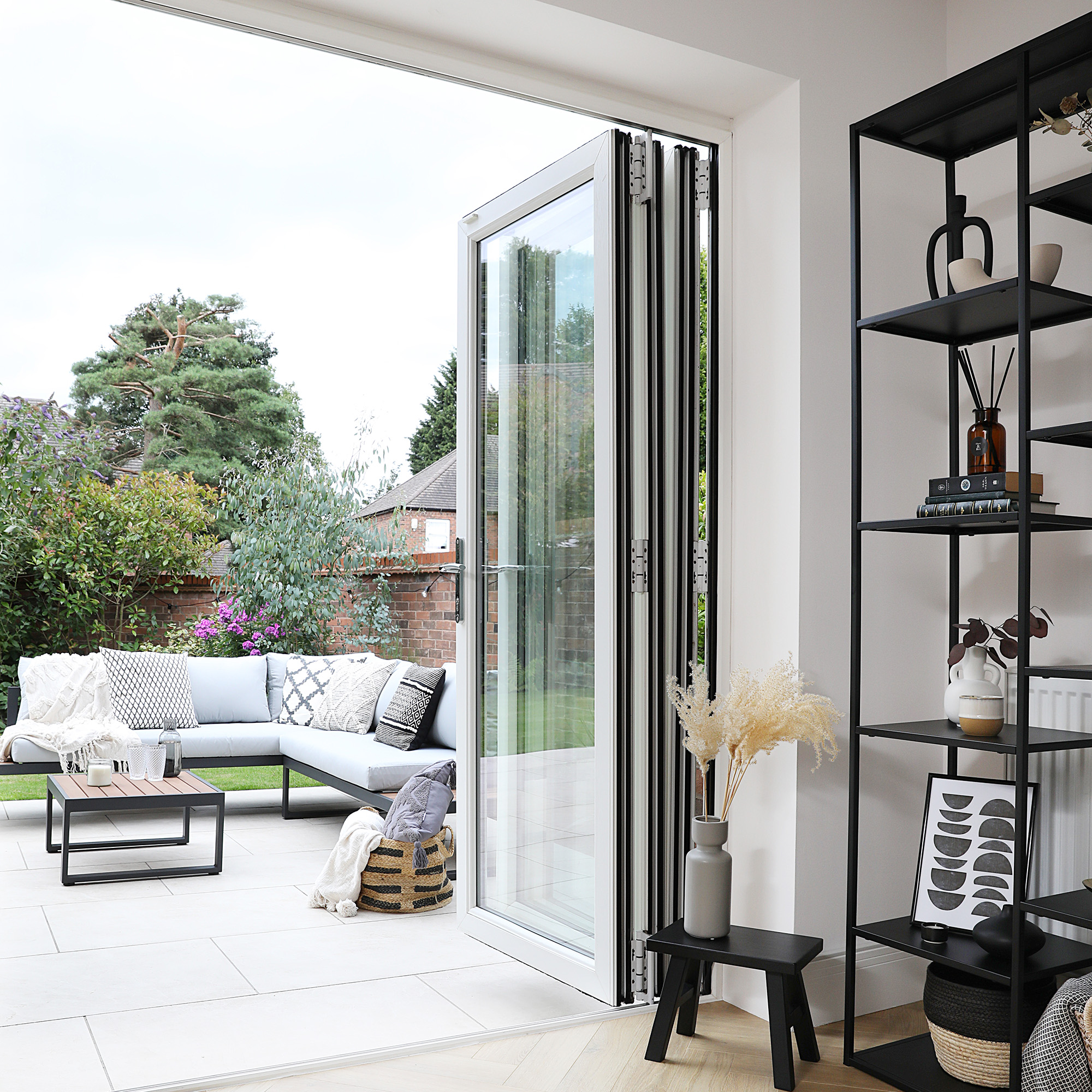 bifold patio doors leading from open plan kitchen to white patio area with black metal framed patio furniture