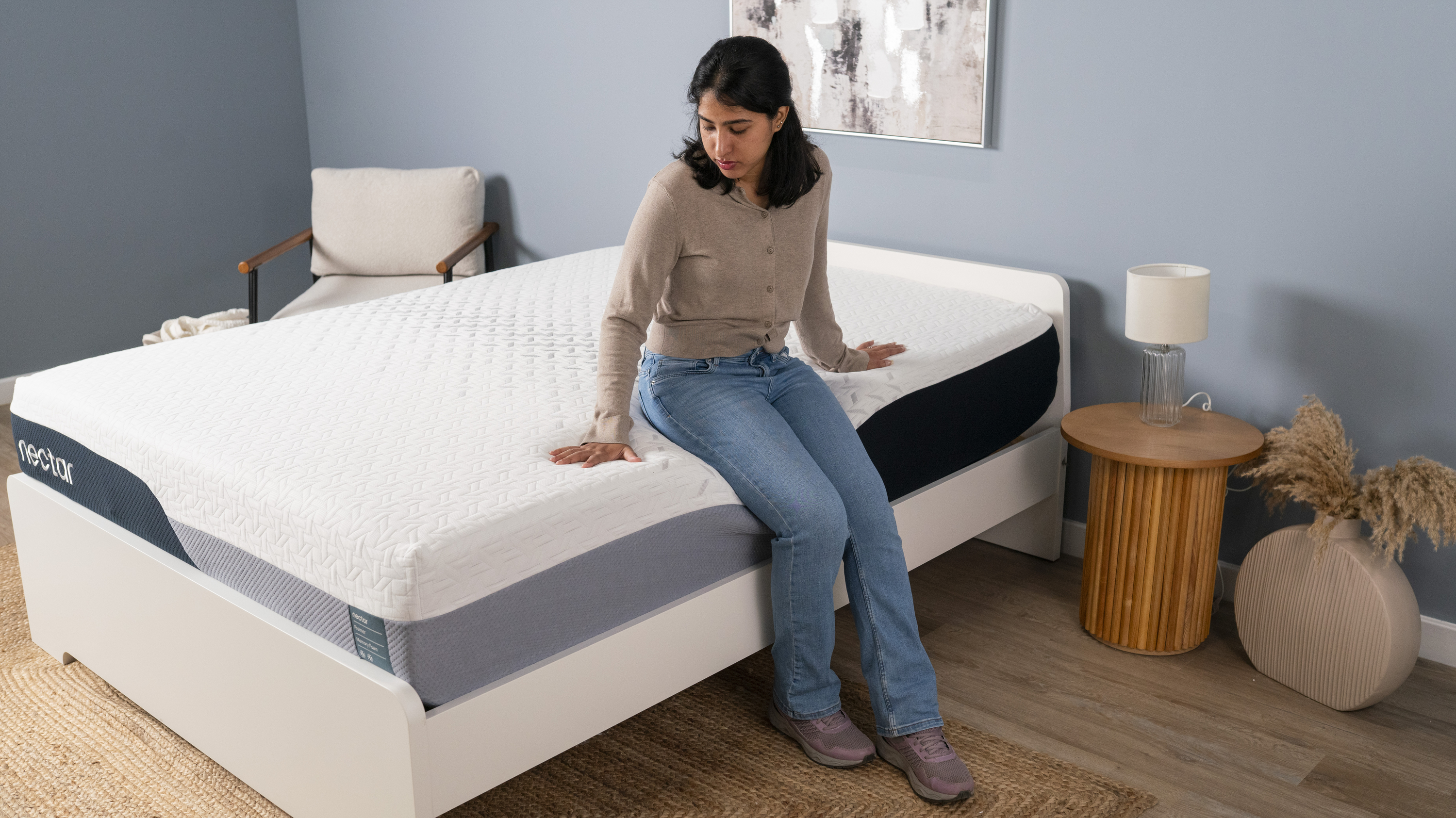 The image shows a mattress tester sat on the edge of the Nectar Premier Memory Foam Mattress