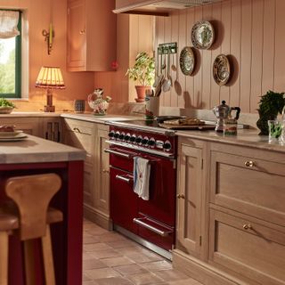 Italian inspired kitchen with pink walls, wooden cabinetry and red range cooker