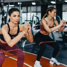 Two women working out with resistance bands in the gym