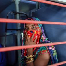 a migrant worker looks out of a compartments window as she sits inside a special train going to agra in uttar pradesh state during a government imposed nationwide lockdown as a preventive measure against the covid 19 coronavirus, at sabarmati railway station on the outskirts of ahmedabad on may 2, 2020 photo by sam panthaky afp photo by sam panthakyafp via getty images