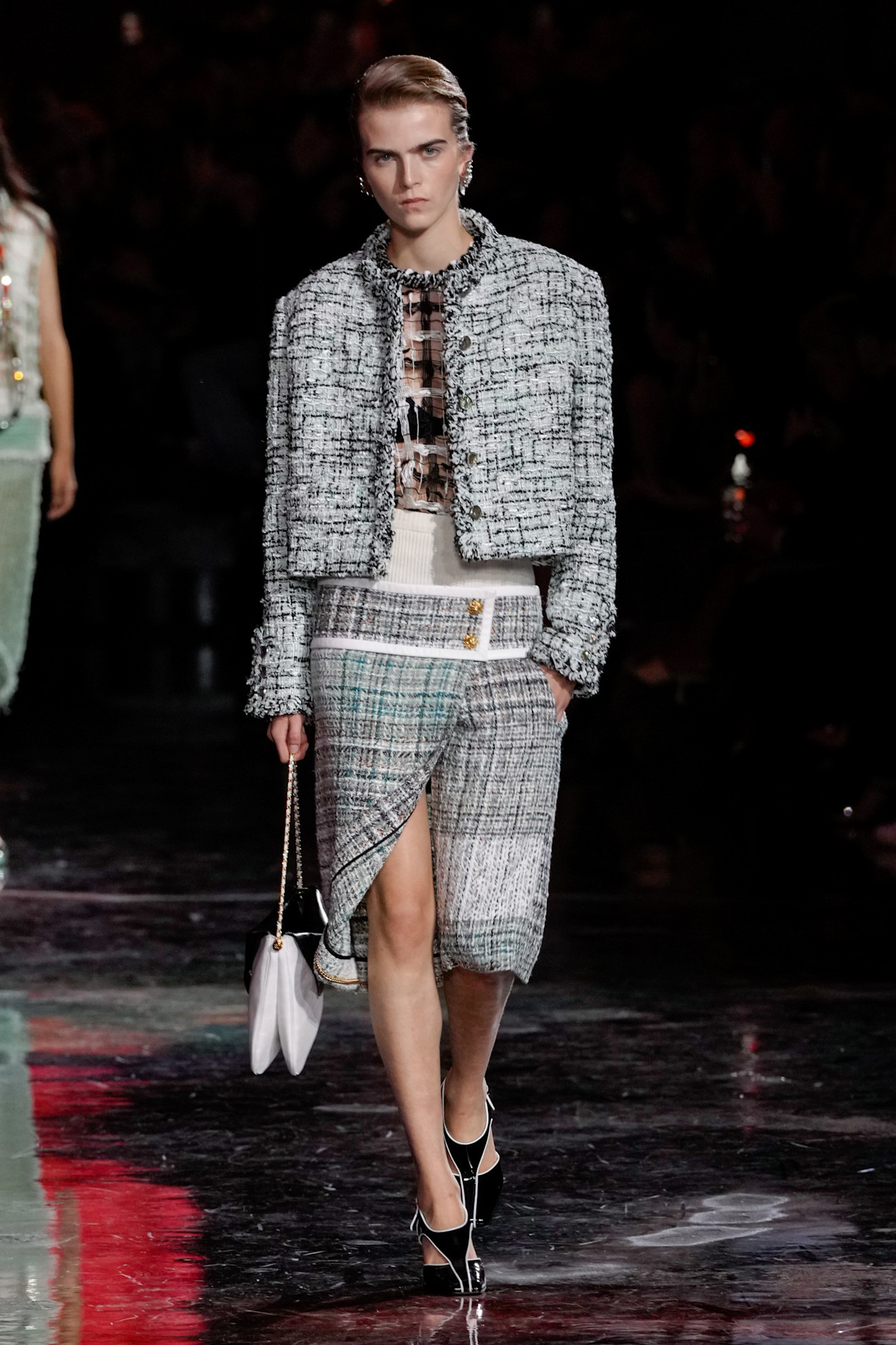 a model wearing a tweed jacket with a white bag