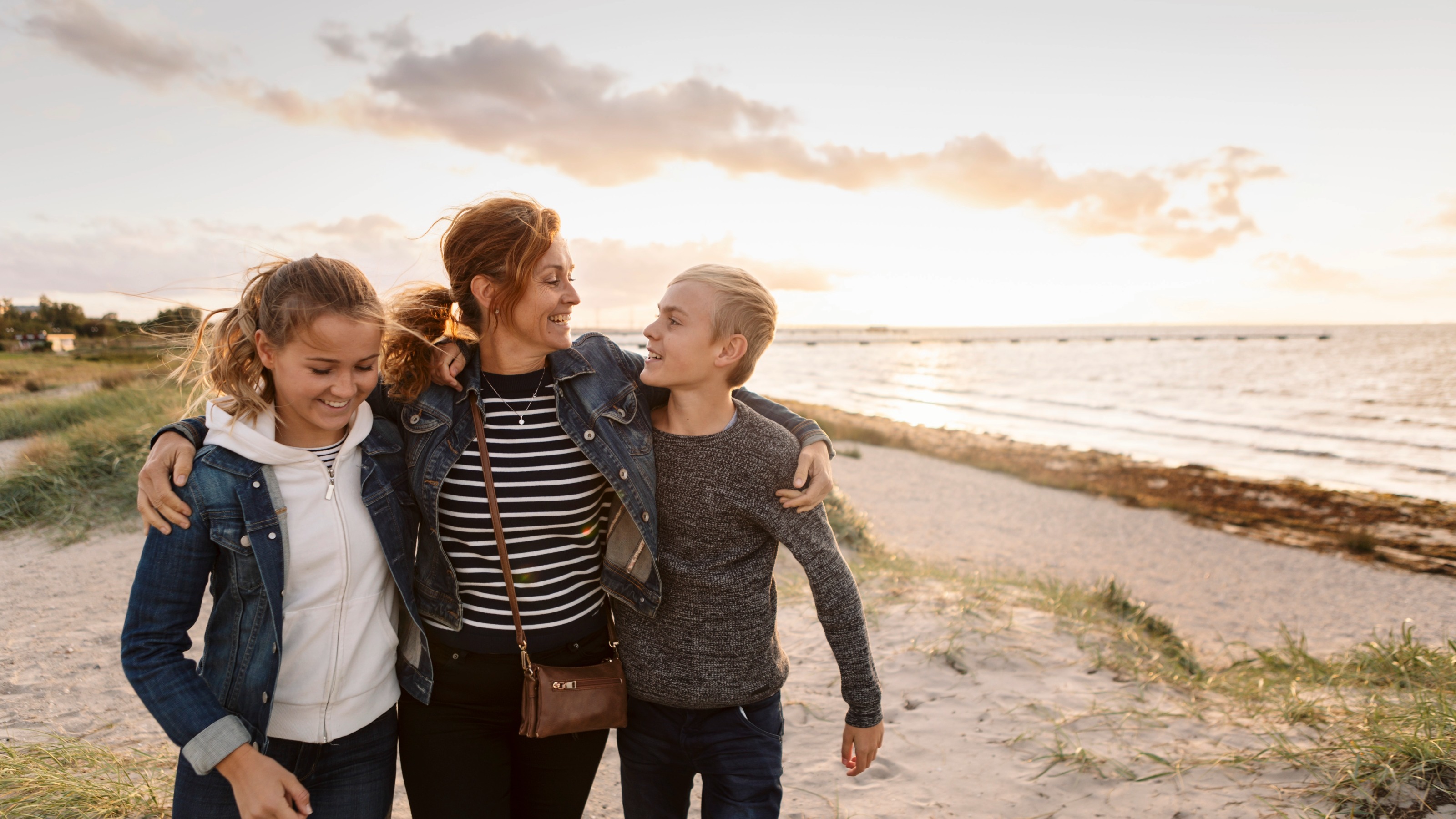 Smiling mother and children enjoying a walk on the beach