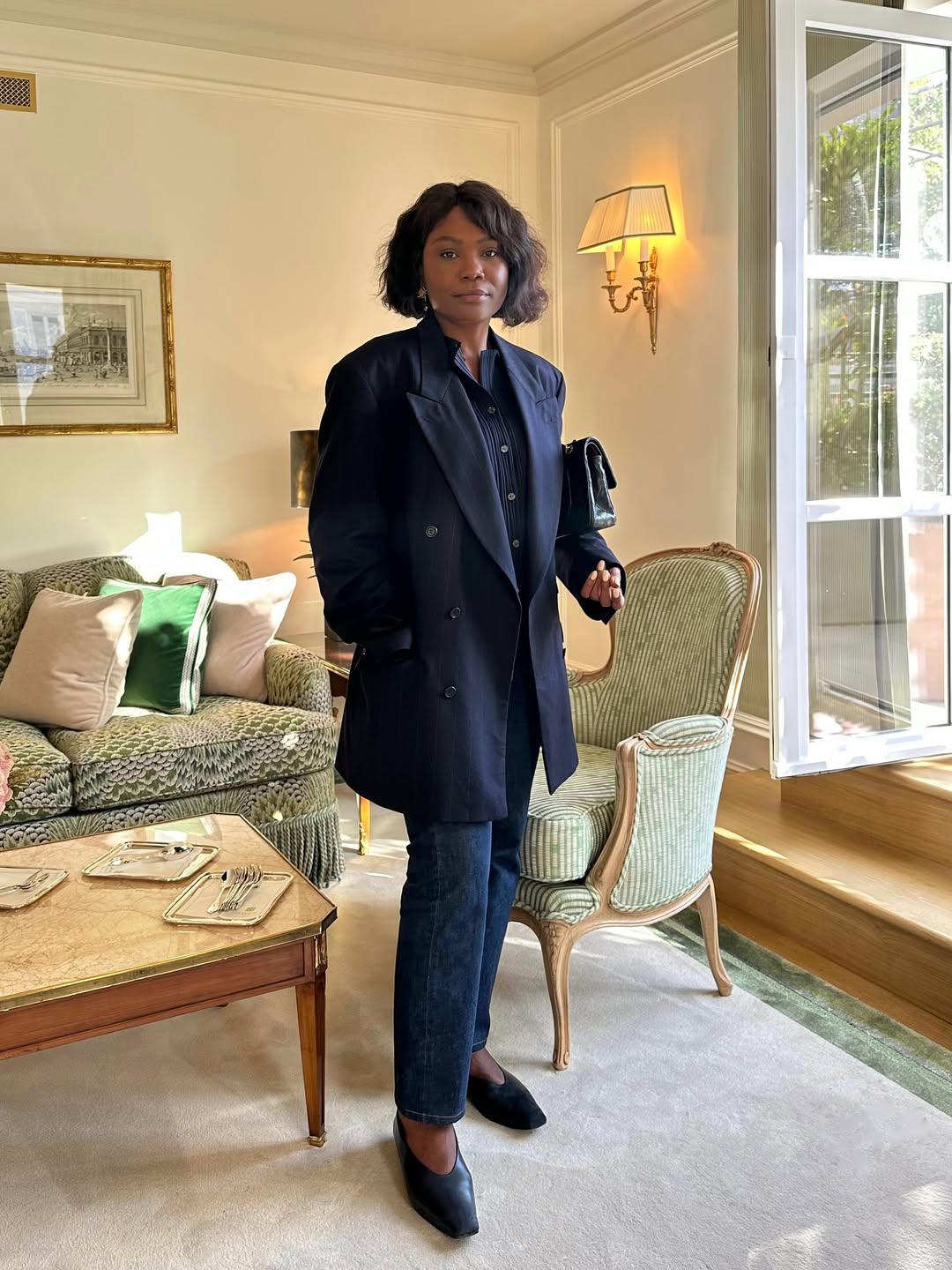 Franny Mozemba is photographed wearing a navy pinstripe blazer and navy button-up top with dark jeans.