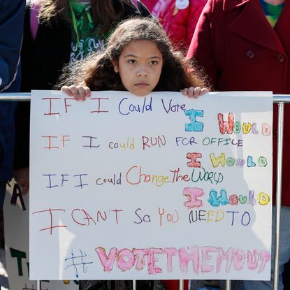 A little girl holding a sign about voting