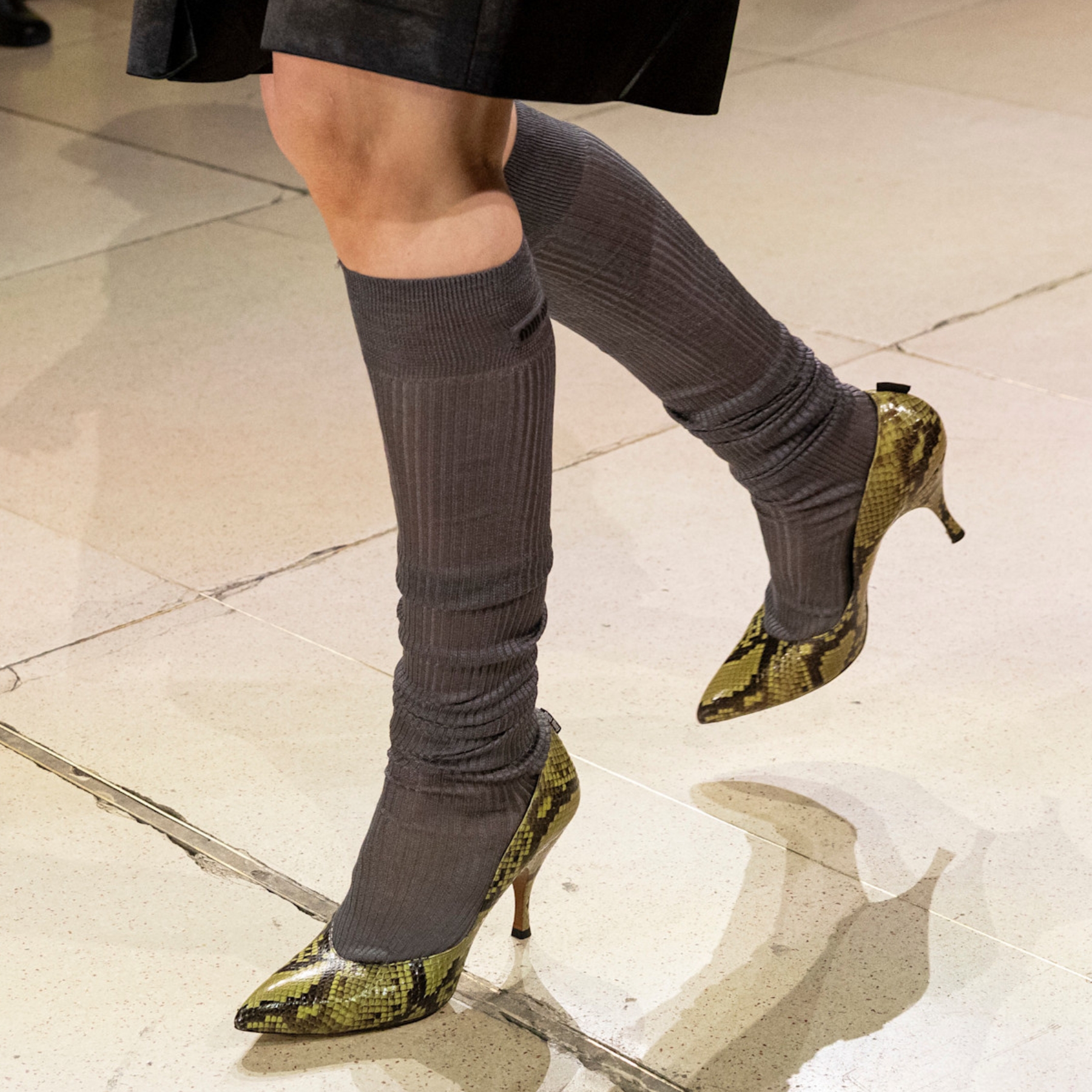 A model walks down the Miu Miu runway, wearing snakeprint heels.