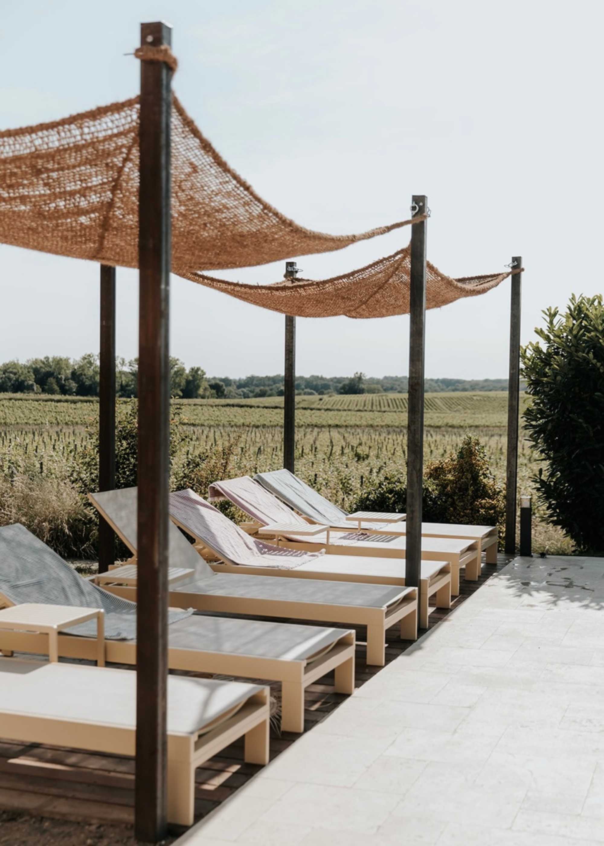 a row of sunbeds in a field beneath a coconut fibre sun shade