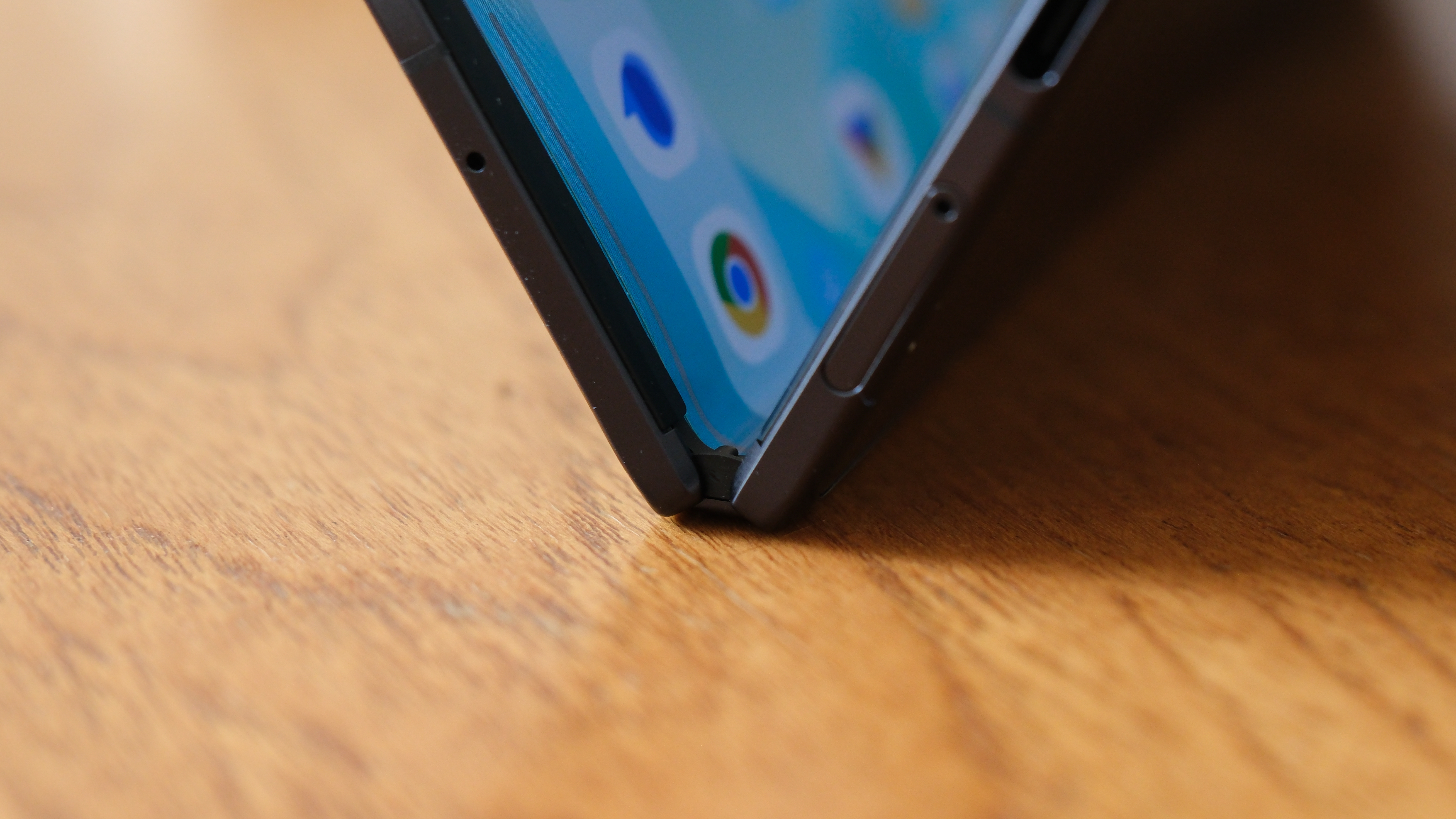 Honor Magic V5 folding phone on a wooden surface with the hinge half folded