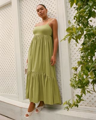 Abercrombie & Fitch model wearing light green sundress posed against white fence