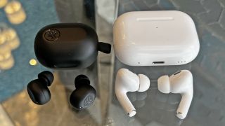 JLab Jbuds Mini next to AirPods Pro 2 on a glass table