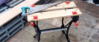 Black & Decker Workmate WN536 with hand saw on top on patio with grey pallet furniture on background