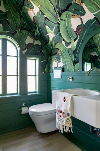 Green bathroom with wallpapered ceiling in a tropical print by chango and co