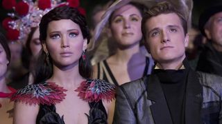 Jennifer Lawrence as Katniss Everdeen and Josh Hutcherson as Peeta Mellark standing together as a couple in The Hunger Games: Catching Fire.