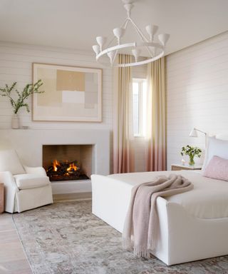 bedroom with white walls and pale rug fire lit